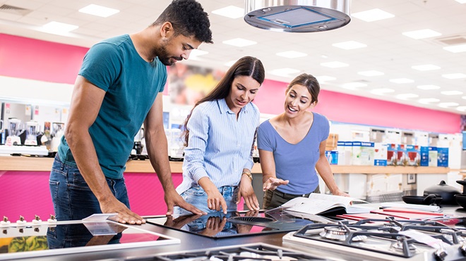 salesperson showing two cooktops to couple